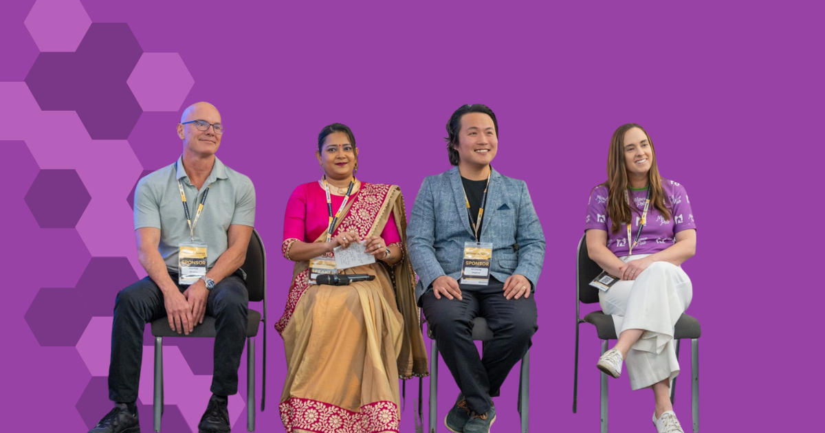 Four panel speakers seated on chairs against a purple background, wearing event lanyards and smiling during a discussion. The group includes people of different ages and cultural backgrounds, with Amy wearing a purple Marco Polo shirt.